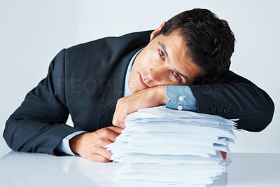Exhausted businessman resting on stack of paperwork
