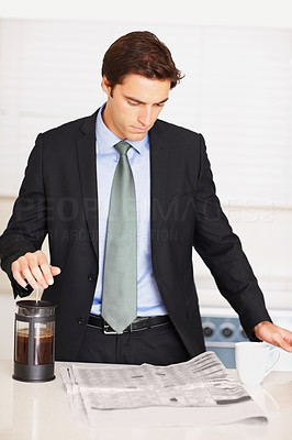 Business man reading newspaper and making coffee in the kitchen