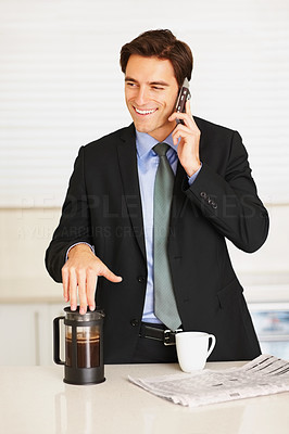 Happy executive using cellphone while drinking coffee at home