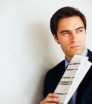 Thoughtful young business man holding a newspaper
