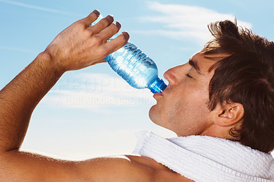 Closeup of a young man drinking water with a towel around neck