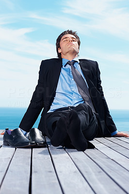 Young business man enjoying the sun on a wooden pier