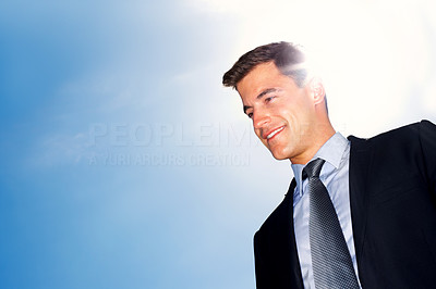 Smiling young business man looking at copyspace against sky