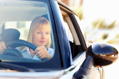 Woman looking at side view mirror while driving a car