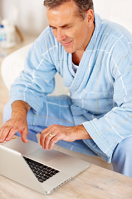 Smiling pensioner using laptop at home