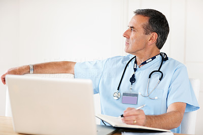 Senior doctor noting his schedule with laptop on desk