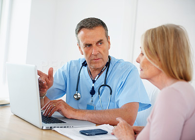 Medical doctor discussing with female patient using laptop