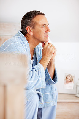 Mature man in bathrobe with hands on chin looking away