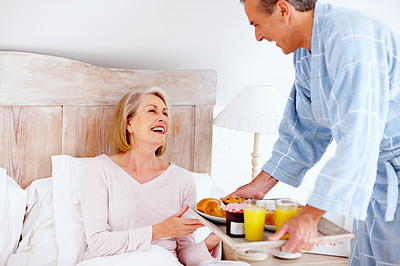 Loving mature man serving breakfast to his wife in bed