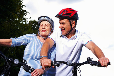 Sporty mature man and woman riding bicycles on a sunny day
