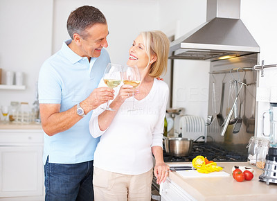 Loving mature couple celebrating together with wine at kitchen