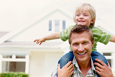 Cheerful father carrying his son on shoulder in front of house