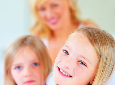 Smiling little girl with her blur sister and mother at back