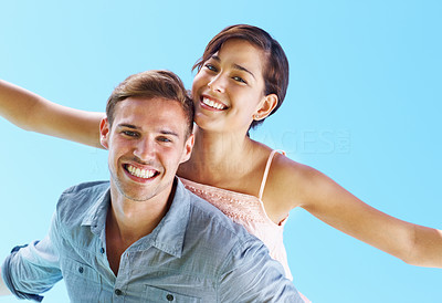 Couple enjoying piggyback ride with arms outstretched