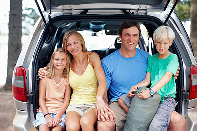 Attractive family sitting in the back of a car and smiling