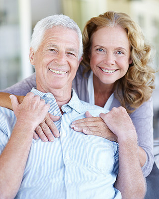 Portrait of smiling senior couple with the wife hugging her husband from behind