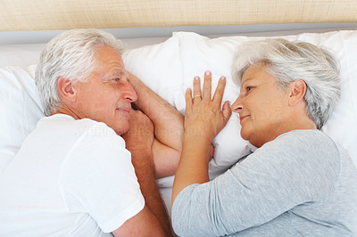 Senior couple lying on bed and looking at each other