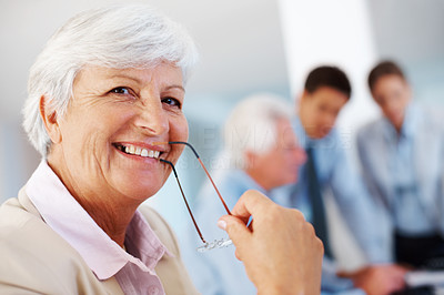 Happy old businesswoman holding glasses in mouth