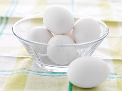 White eggs in a glass bowl on a tablecloth