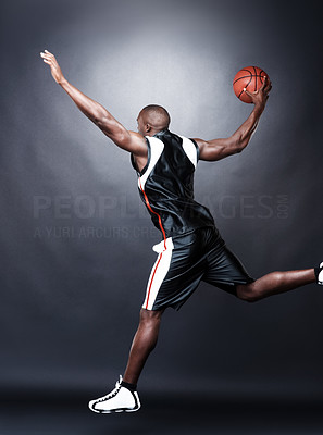 Young basketball player in action on black background