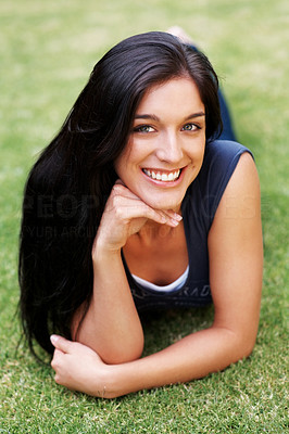 Happy young lady lying on grass at the park
