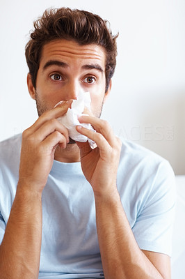 Surprised man wiping his nose with tissue