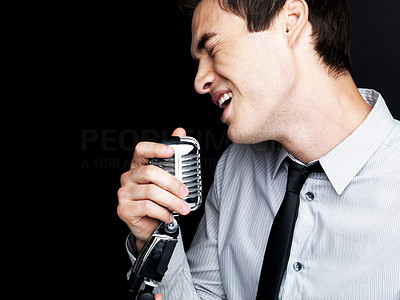 Young male star singer singing into old fashioned microphone