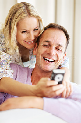 Happy couple reading a funny sms on cellphone