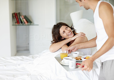 Pretty woman in bed with her husband serving breakfast