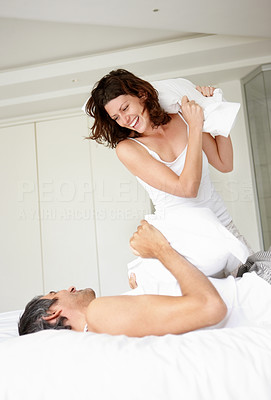 Cheerful mature couple having a pillow fight