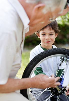 Little boy watching a old man fix a bicycle tyre