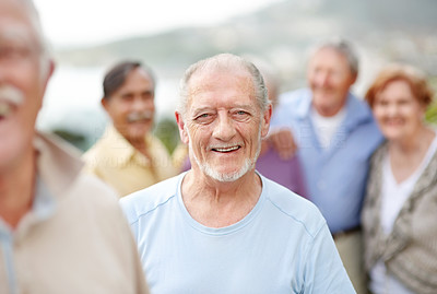 Happy old man enjoying outdoors with people in background