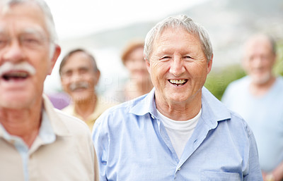 Retired aged man laughing outside with old people