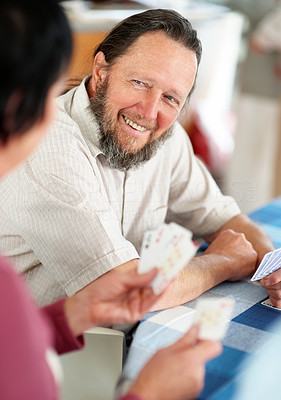 Happy senior man playing cards with his wife