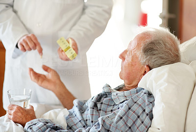 Young doctor giving pill to the senior man