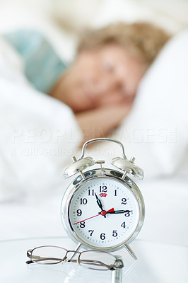 Table clock and spectacles with a woman sleeping on back