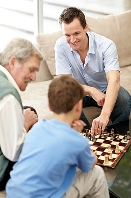 Mature man playing a chess with his son