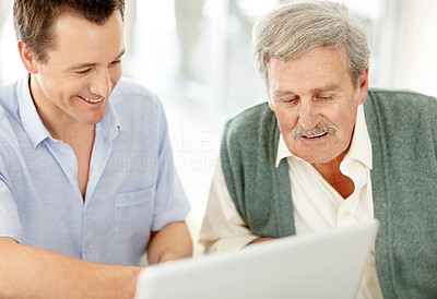 Smiling man showing something interesting on laptop to his father