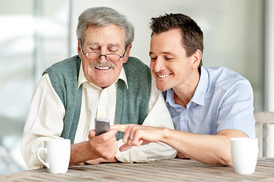 Young son teaching his father to operate a mobile
