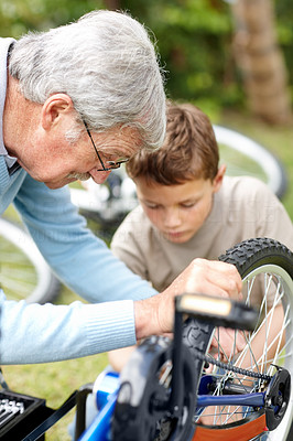 Senior man repairing a bicycle tyre with his grand son