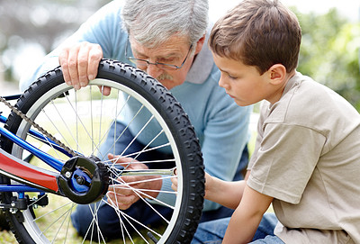 Aged man repairing a bicycle tyre with his grand son