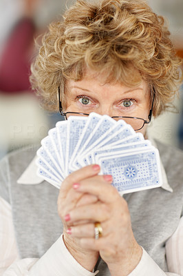 Old woman hiding her face with playing cards