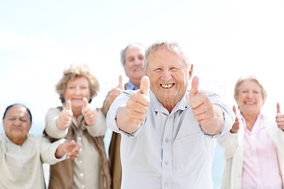 Excited old man showing thumbs up sign with friends