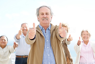 Senior man showing thumbs up sign with friends