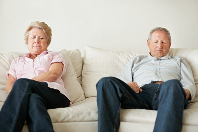 Unhappy old couple sitting separately after an argument