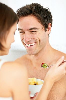 Closeup of a happy young couple eating fruit salad