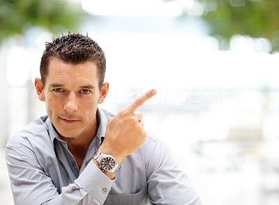 Confident young business man pointing at copyspace
