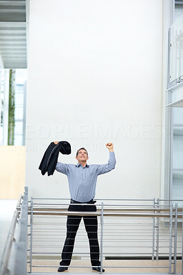 Excited young business man with hands raised in victory