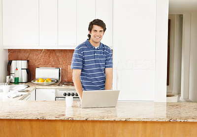 Young smiling guy with laptop at the kitchen