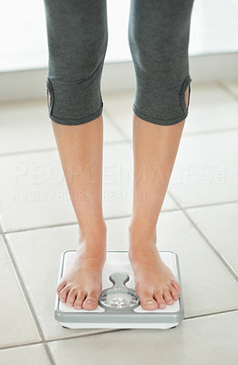 Low section of a female weighing herself on the scale